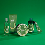 A set of The Body Shop Matcha body care products arranged on a solid green background, including a clear bottle, a green tube, a dark bottle, a round tin, and a small angled tube.