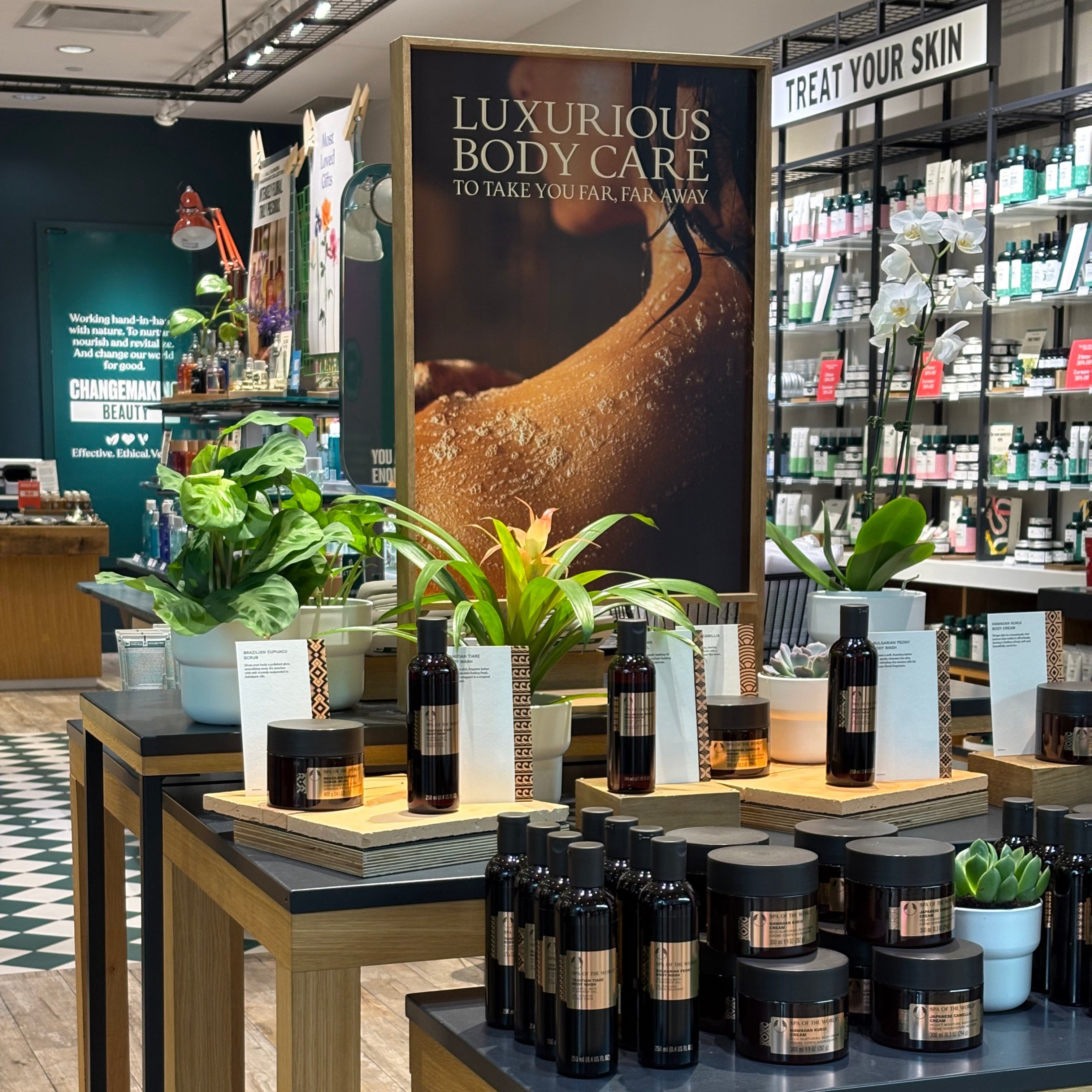 Display of bottles on a shelf with a magazine titled 'Luxurious Body Care' in a store setting.