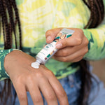 Person applying a tube of cream to their hand with a focus on the product and action.