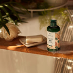 Body shop bottle on a wooden shelf with soap and plants
