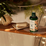 Body shop bottle on a wooden shelf with soap and plants