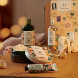 The Body Shop products including shower cream, body butter, and bath salts on a wooden surface with a blurred background.