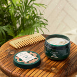 Shea butter product with a comb on a wooden board with plants in the background