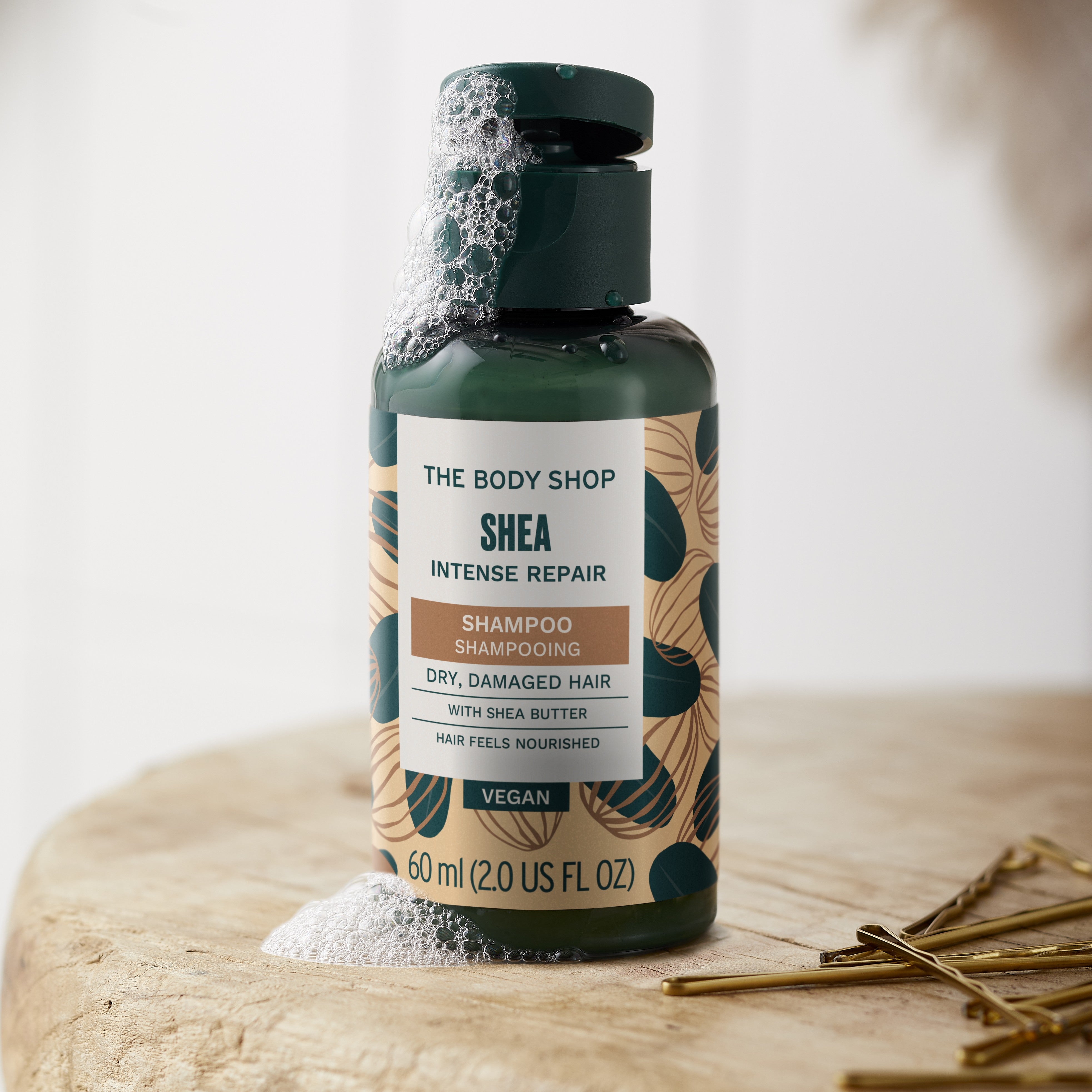 The Body Shop Shea Intense Repair Shampoo bottle on a wooden surface with a blurred background