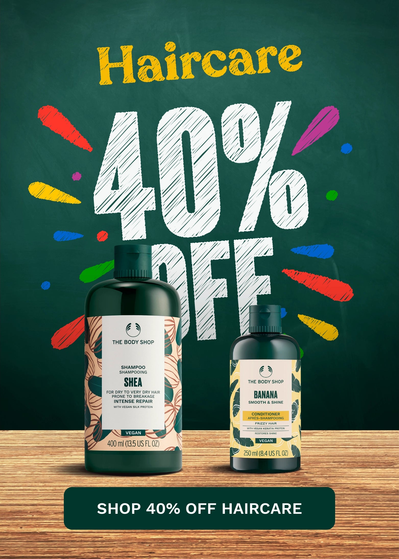 Promotional haircare graphic with two bottles from The Body Shop on a wooden surface against a dark green chalkboard-style background. Large text reads 'Haircare 40% OFF' with colorful paint splatter accents, and a banner at the bottom says 'SHOP 40% OFF HAIRCARE.