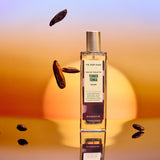 Bottle of 'The Body Shop' Tender Touch perfume with scattered almonds on a gradient background
