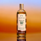 Bottle of The Body Shop Tender Tonka fragrance mist on a gradient background