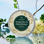 Body butter container with white tea and elderflower design on a natural background