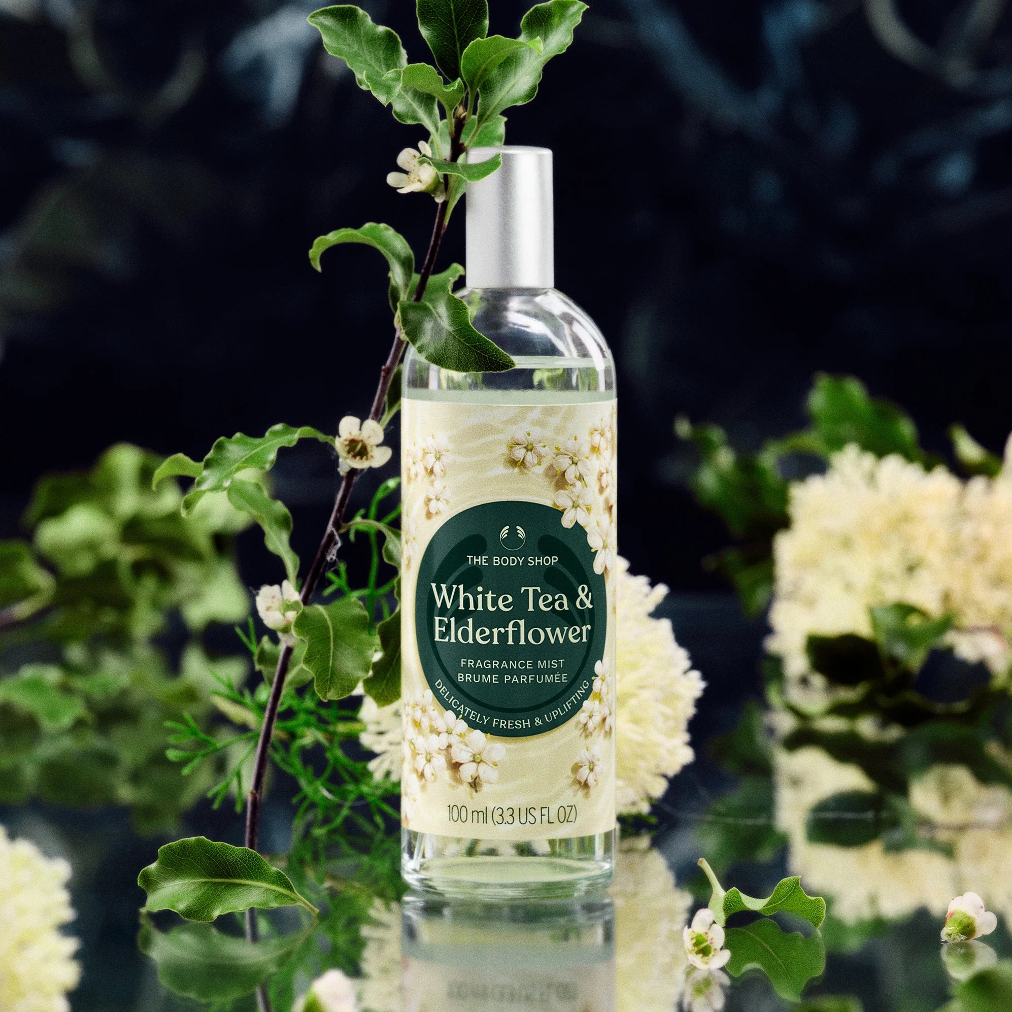 Fragrance mist bottle labeled 'White Tea & Elderflower' with green leaves and flowers in the background