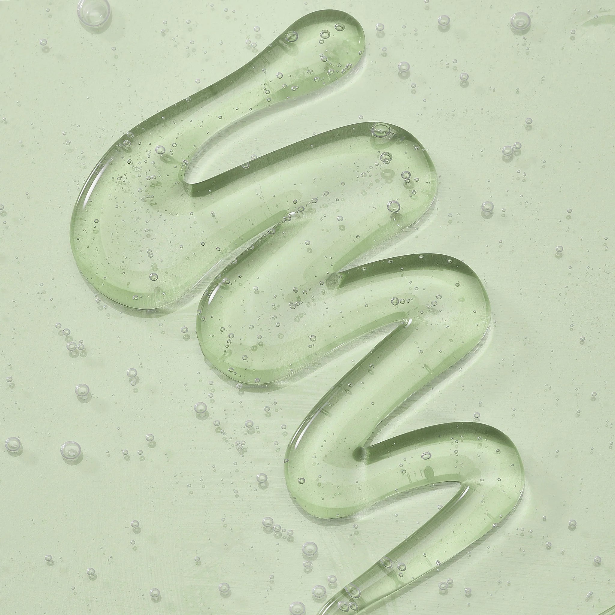 Green skincare gel in a wavy pattern on a light green background