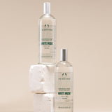 Two bottles of The Body Shop White Musk fragrance mist on a beige background