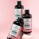Three bottles of The Body Shop British Rose shower gel on a pink background