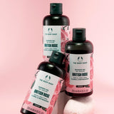 Three bottles of The Body Shop British Rose shower gel on a pink background