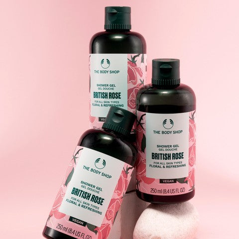 Three bottles of The Body Shop British Rose shower gel on a pink background