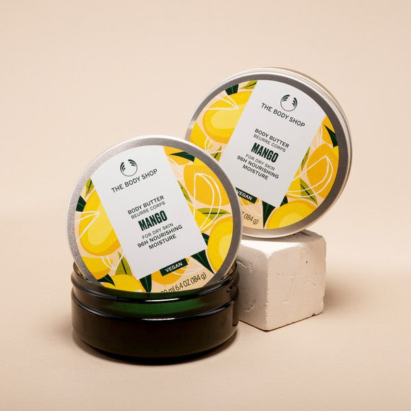 Two containers of The Body Shop Mango body butter on a beige background
