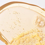 Close-up of a creamy beige substance with gold specks on a white background