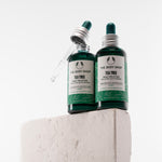 Two bottles of The Body Shop Tea Tree Skincare Solution on a light gray background