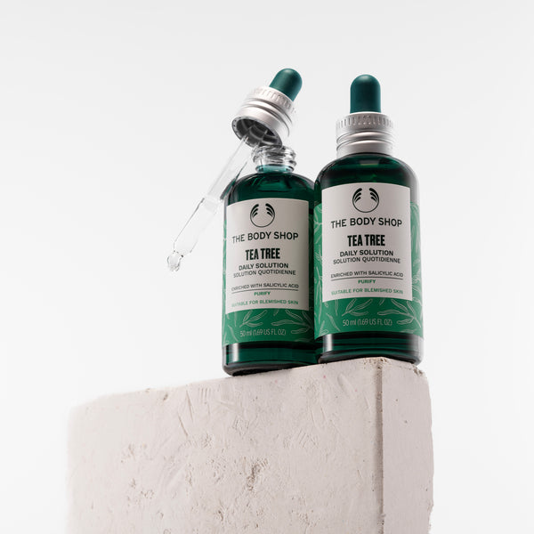 Two bottles of The Body Shop Tea Tree Skincare Solution on a light gray background