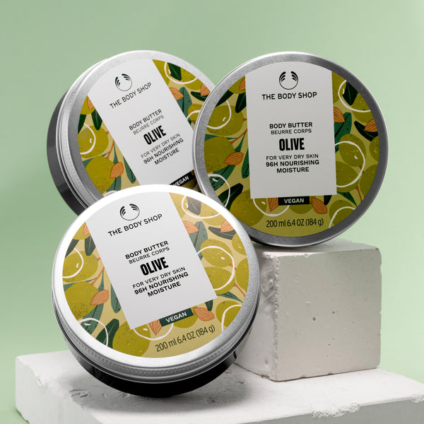 Three tins of The Body Shop Olive body butter on a light green background