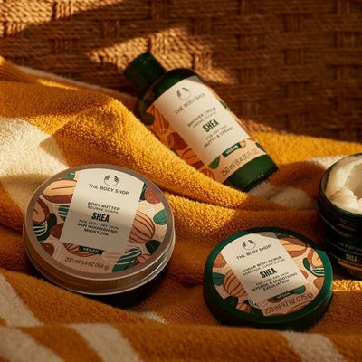 Shea body butter containers and a bottle on a textured fabric background