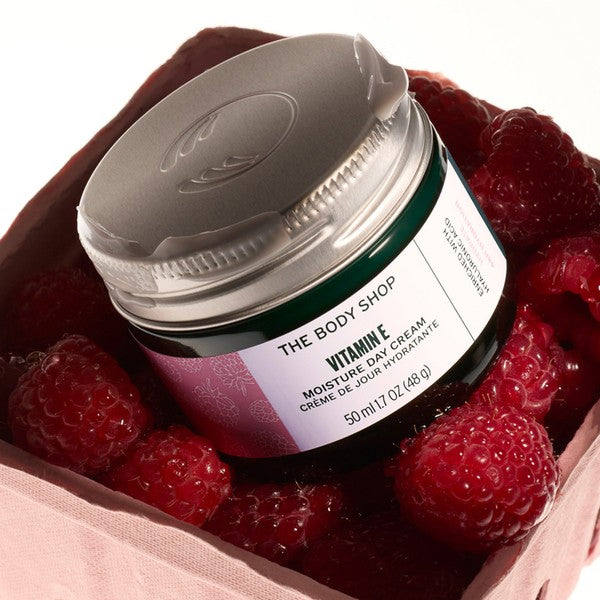 Jar of The Body Shop Vitamin E cream surrounded by raspberries